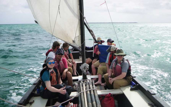 a group of veterans sit on a sailboat on an outward bound expedition 